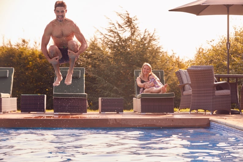 Man doing cannonball into swimming pool