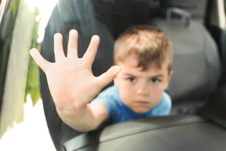 Boy placing hand on car window