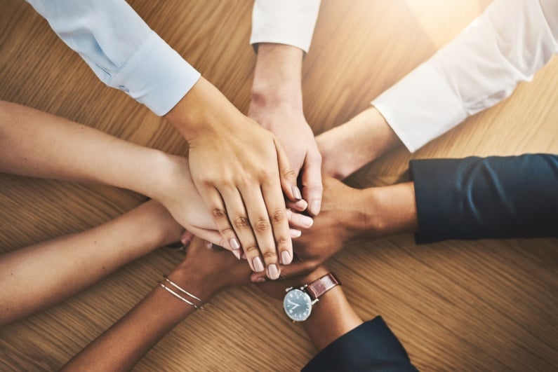 Business people putting hands in the middle