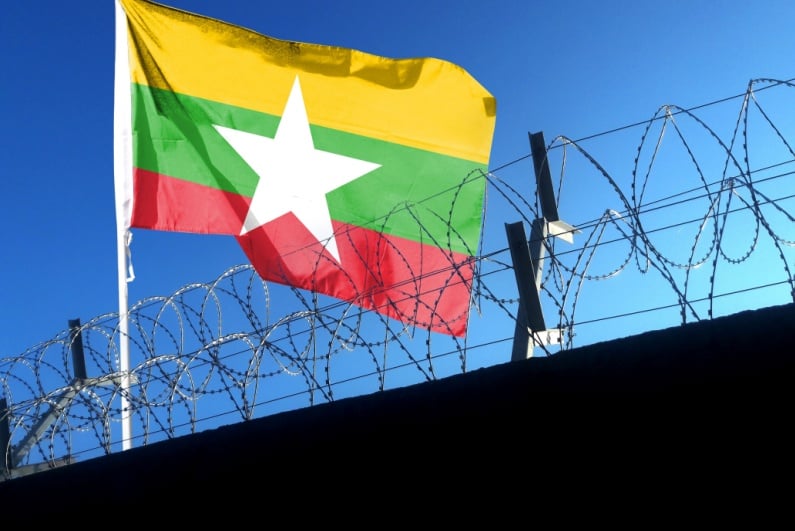 Myanmar flag over a security fence