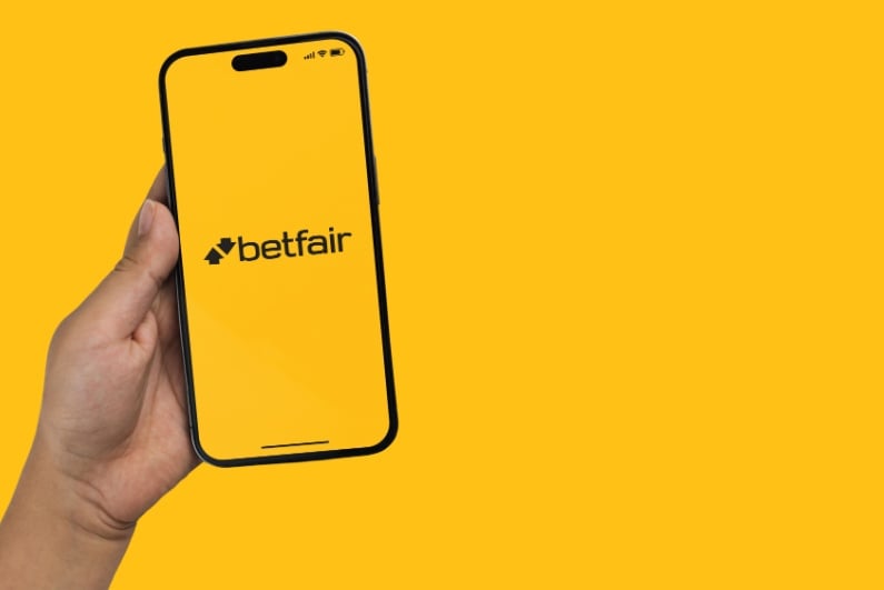 Person holding phone with Betfair logo