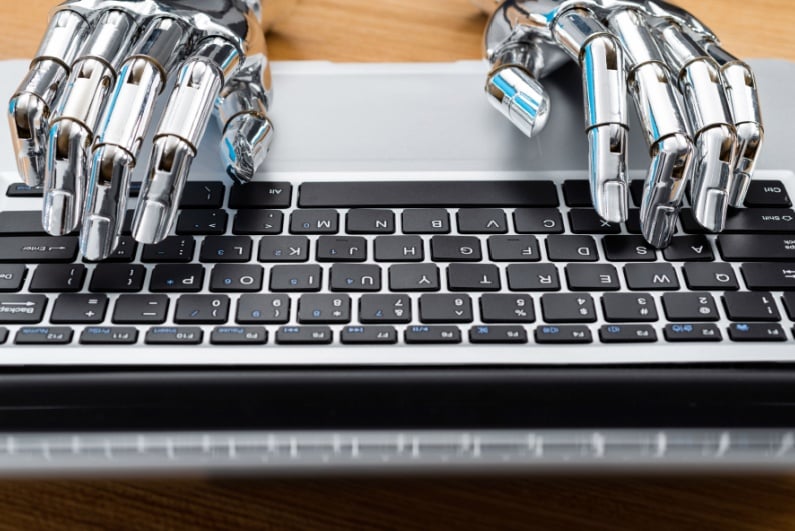 Robot hands typing on computer