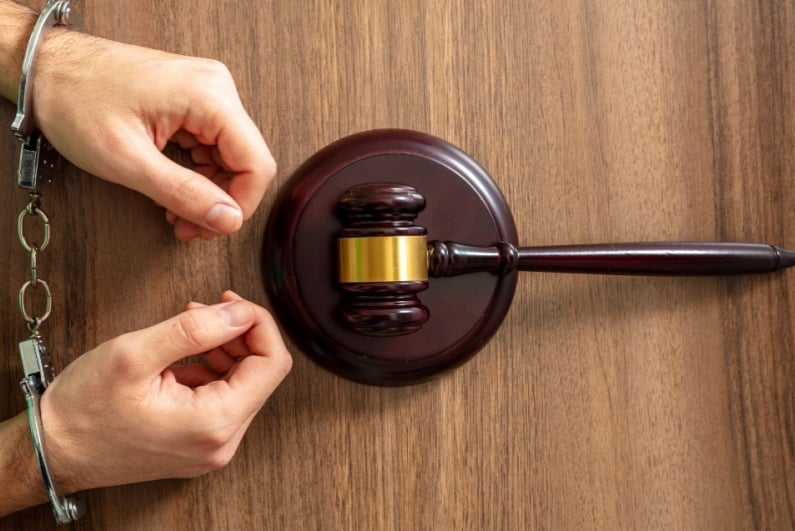 Handcuffed person and wooden gavel