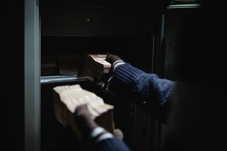 Thief stealing cash from safe