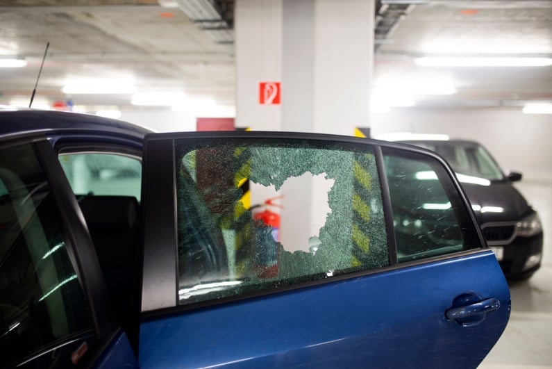 Broken car window in parking garage