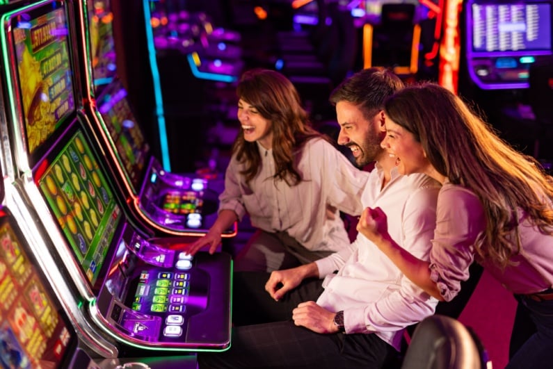 Man and two women celebrating at slot machine