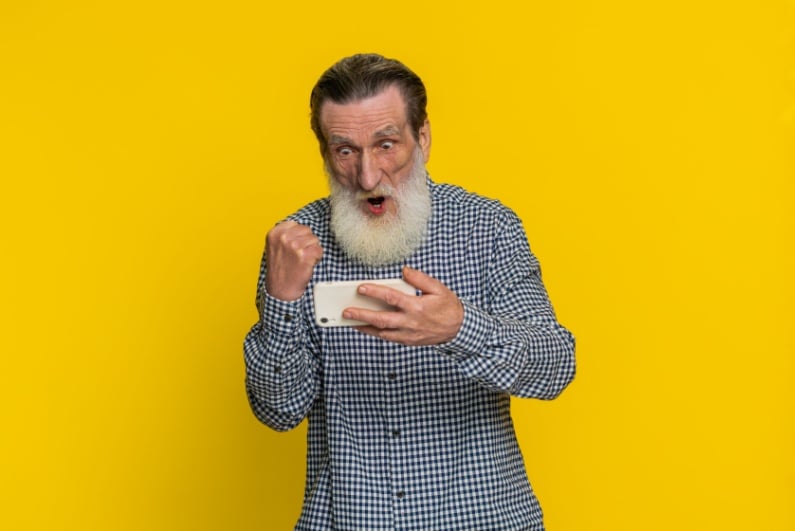 Old man looking at phone and celebrating