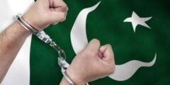 Man in handcuffs in front of Pakistan flag