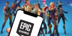 Epic Games logo on phone with Fortnite in background