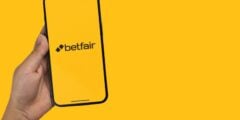Person holding phone with Betfair logo