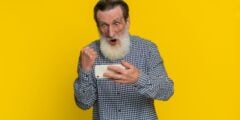 Old man looking at phone and celebrating